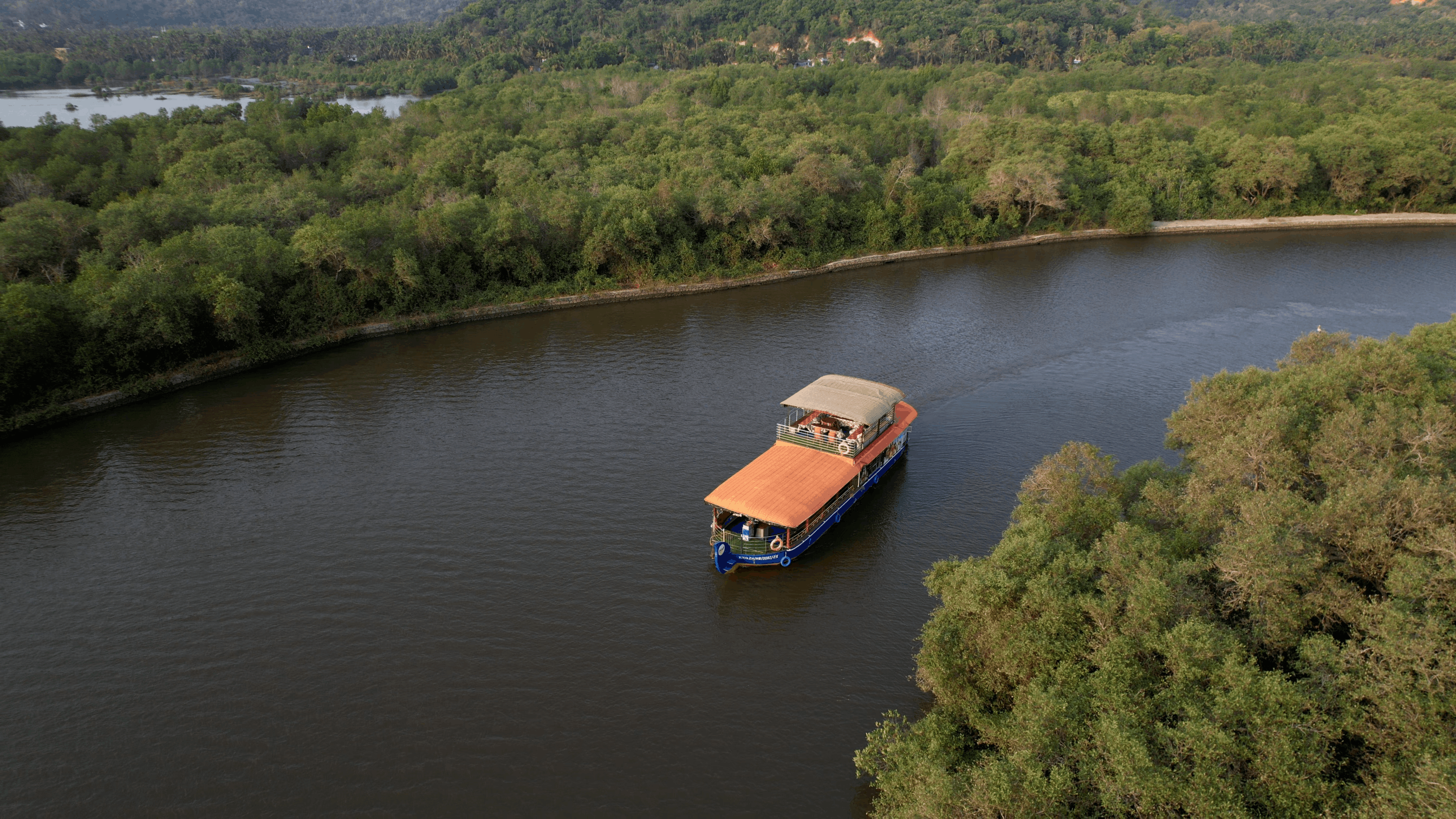 Day cruise boat among mangrove roots on the Vellikkeel river